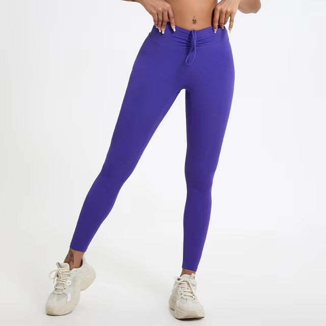 A woman posing in high-waisted, purple leggings