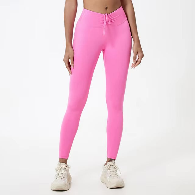 A woman posing in high-waisted, pink leggings