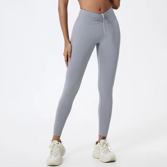 A woman posing in high-waisted, grey leggings