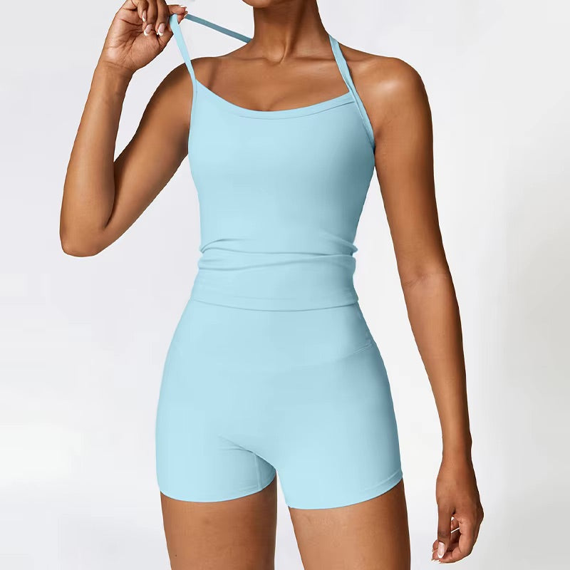 A woman posing in a light blue, two-piece workout set that includes shorts and a sleeveless shirt