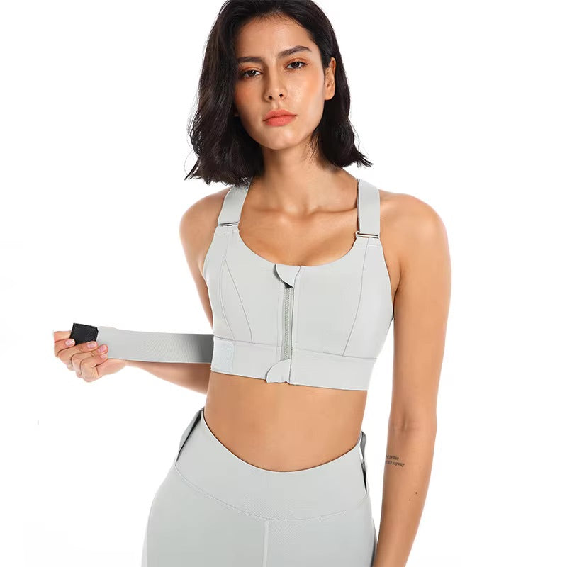 A woman posing in a grey sports bra with a zipper