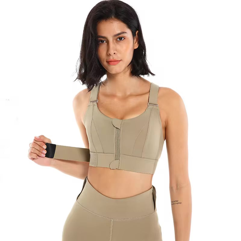 A woman posing in an brown sports bra with a zipper