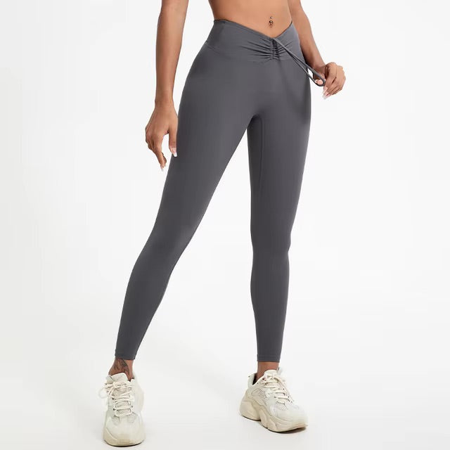 A woman posing in high-waisted, grey leggings