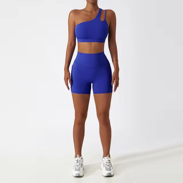 A woman posing in a matching set consisting of a cut-out sports bra and shorts in dark blue color