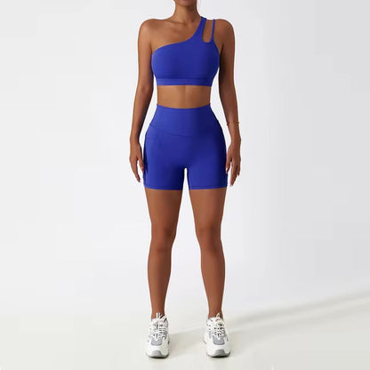 A woman posing in a matching set consisting of a cut-out sports bra and shorts in dark blue color