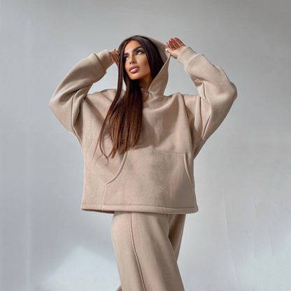 A woman posing in a beige, oversized hoodie with matching sweatpants