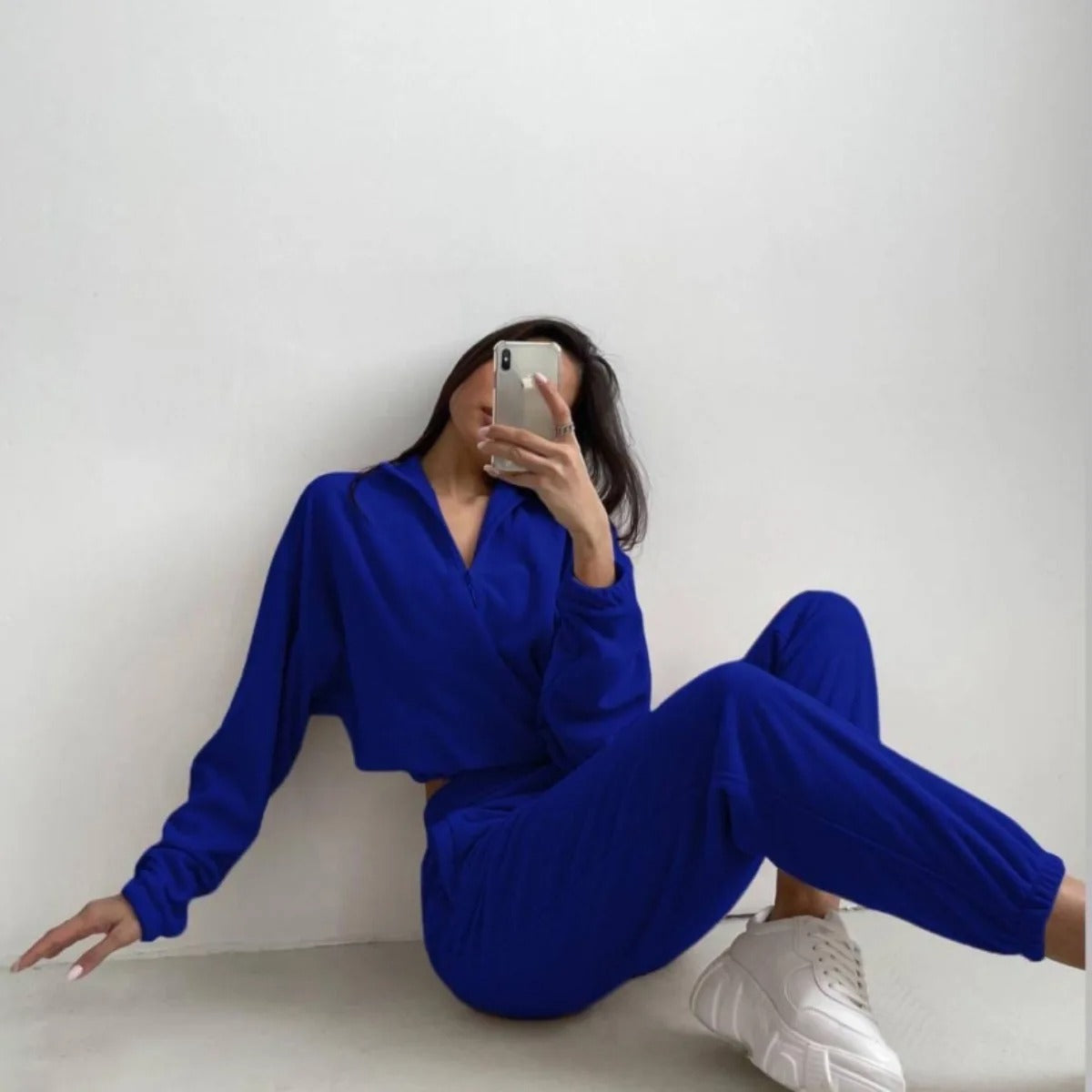 A woman posing in a blue matching set consisting of a sweatshirt and sweatpants