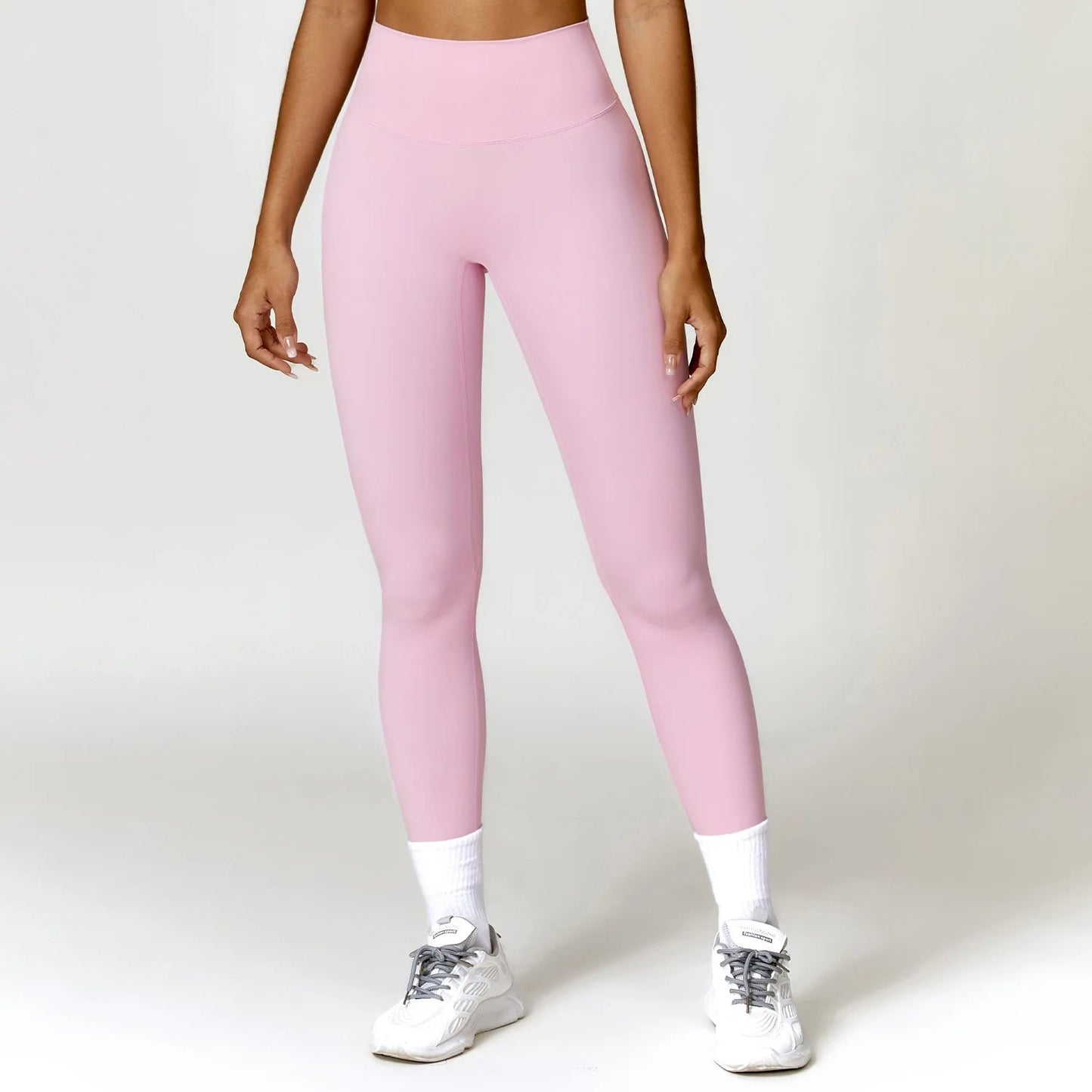 A woman posing in light pink leggings