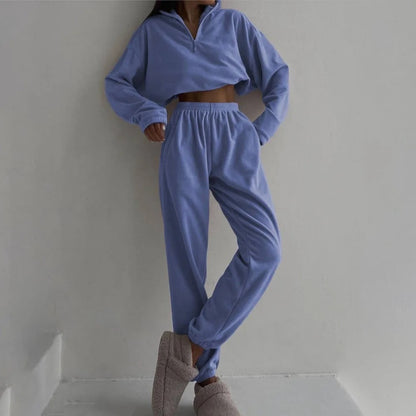 A woman posing in a light blue matching set consisting of a sweatshirt and sweatpants