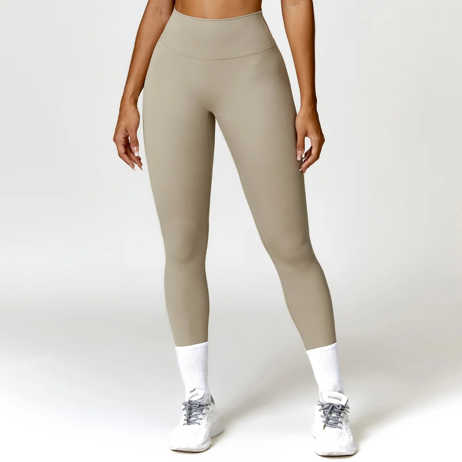 A woman posing in beige leggings