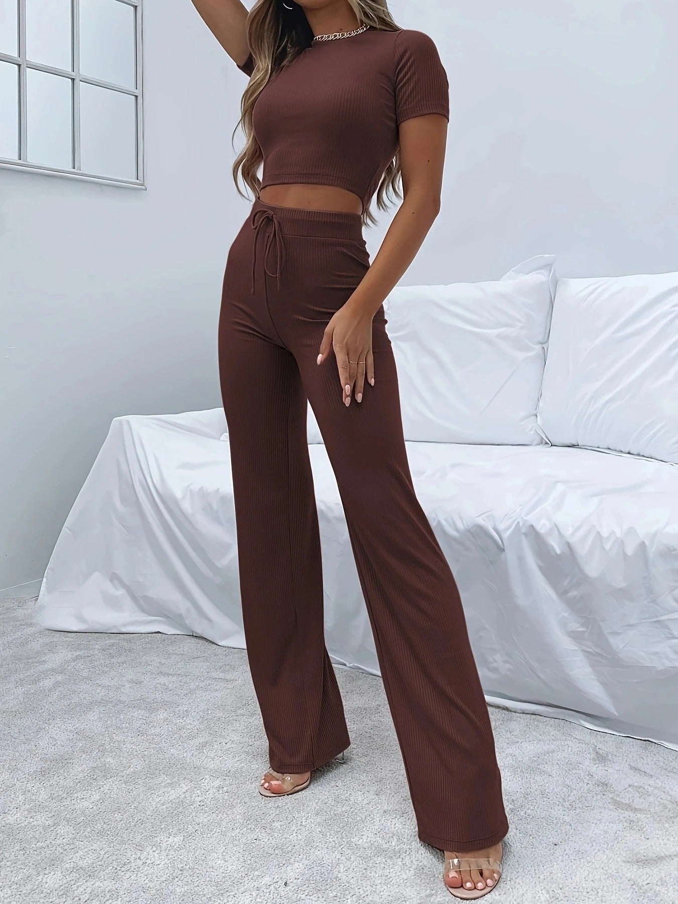 Woman posing in a brown, two-piece lounge set consisting of sweatpants and a t-shirt