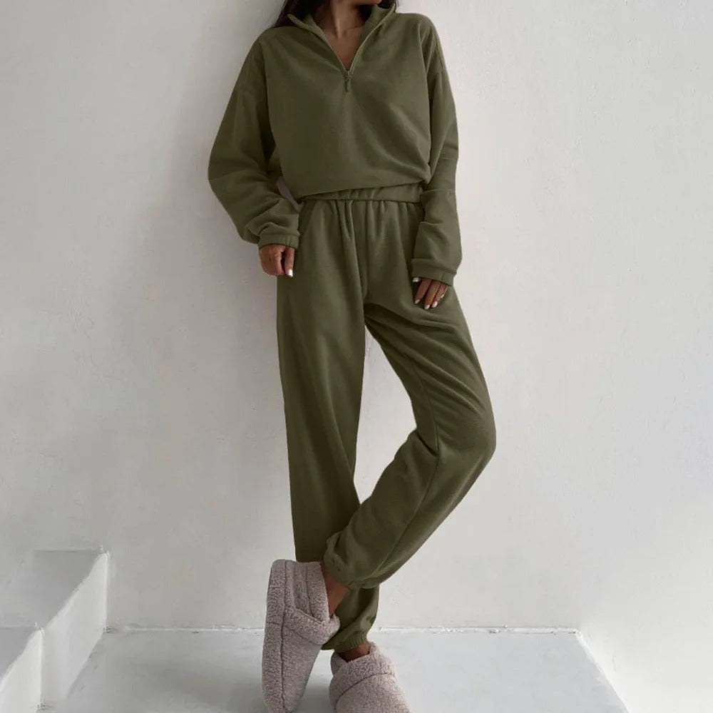 A woman posing in an olive green matching set consisting of a sweatshirt and sweatpants