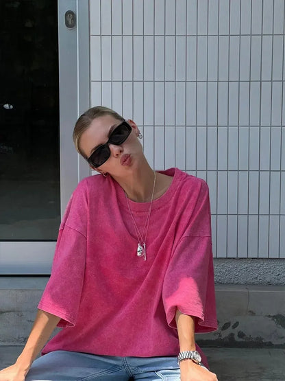 A woman posing in a pink, oversized t-shirt