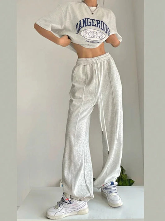 Woman posing in wide legged, white sweatpants