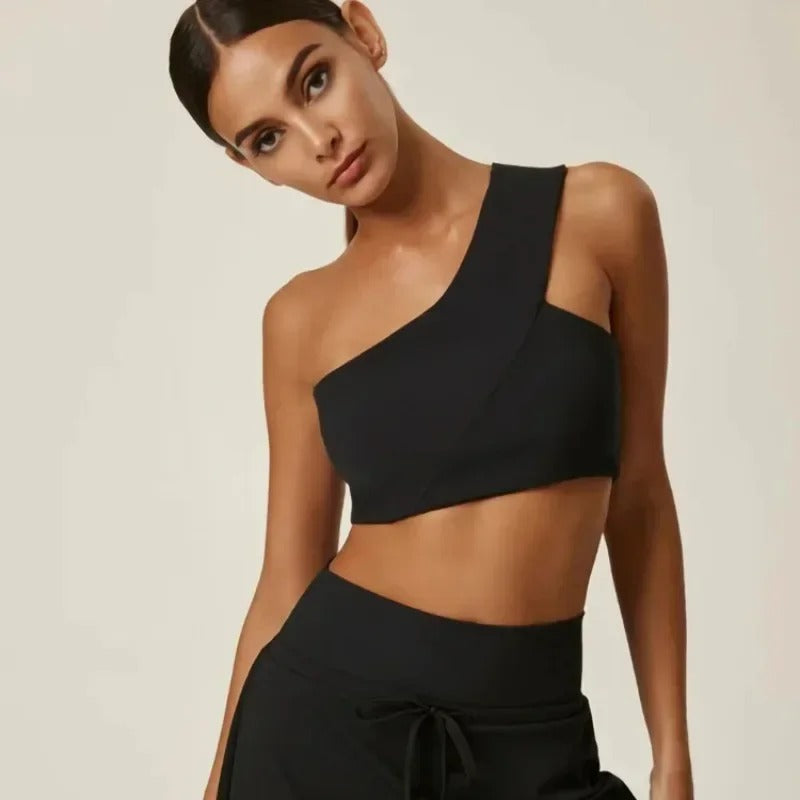 A woman posing in a black, one shoulder sports bra