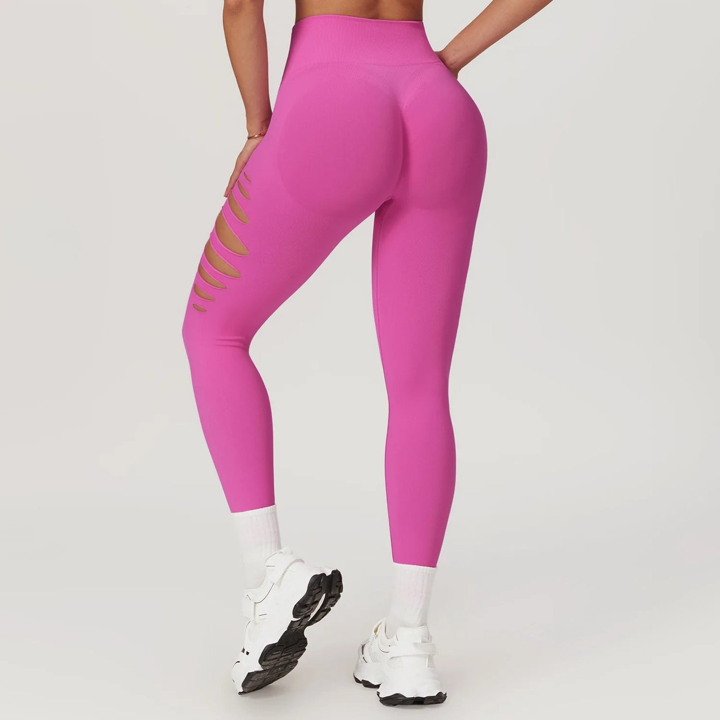 A woman in neon pink yoga pants with holes on the sides