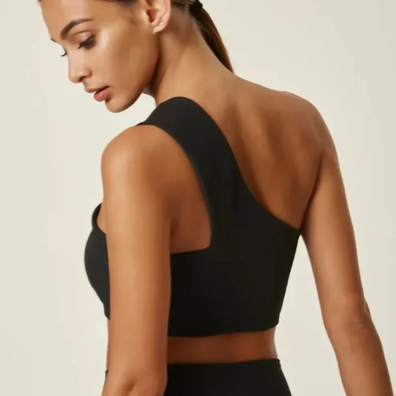 A woman posing in a black, one shoulder sports bra