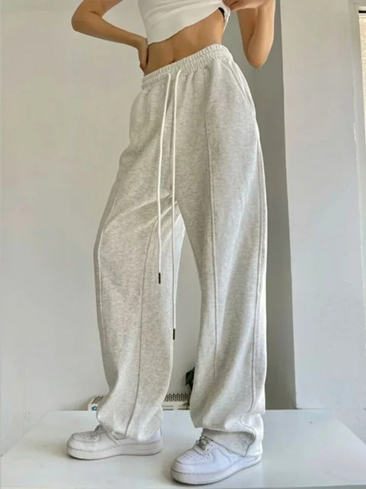 Woman posing in wide legged, white sweatpants