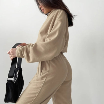 A woman posing in a beige matching set consisting of a sweatshirt and sweatpants