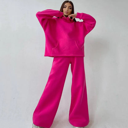 A woman posing in a neon pink, oversized hoodie with matching sweatpants