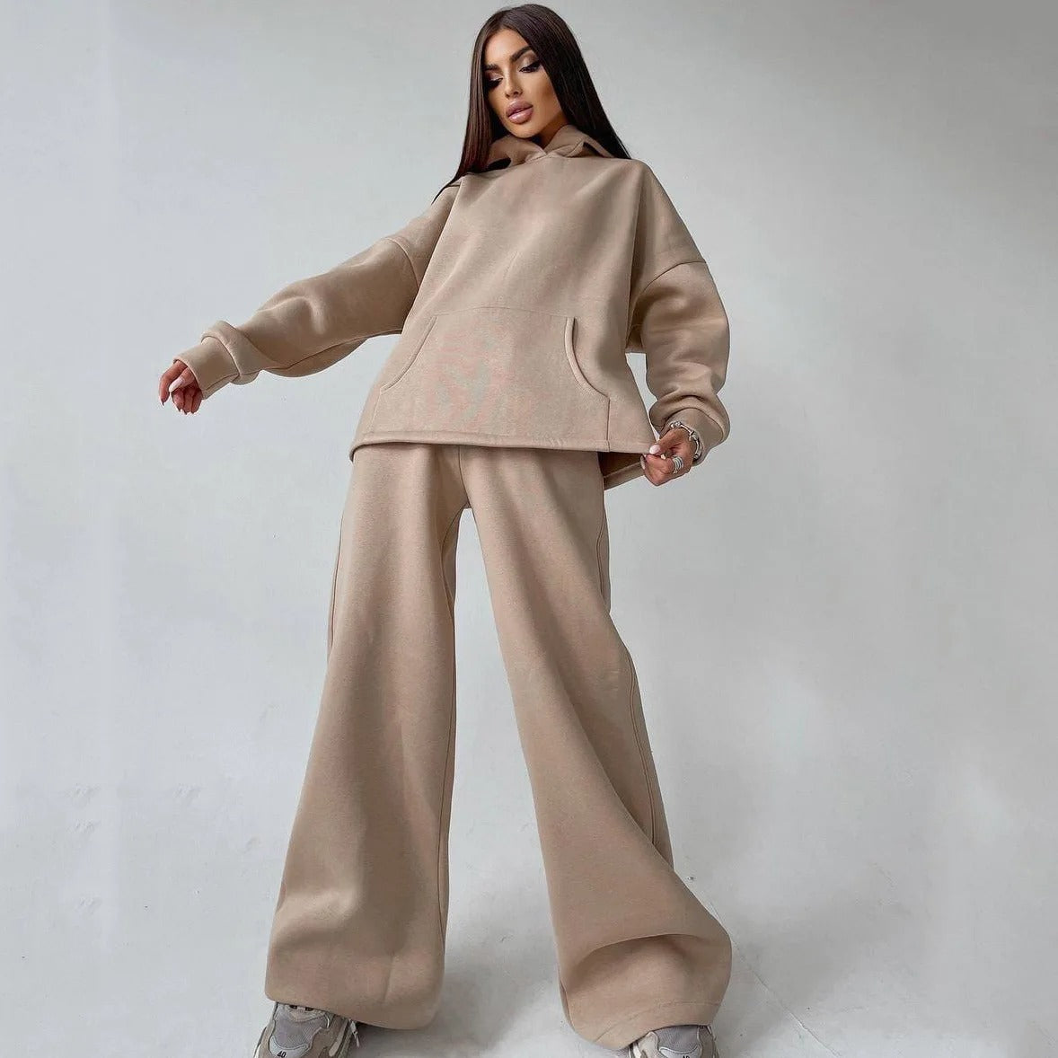 A woman posing in a beige, oversized hoodie with matching sweatpants