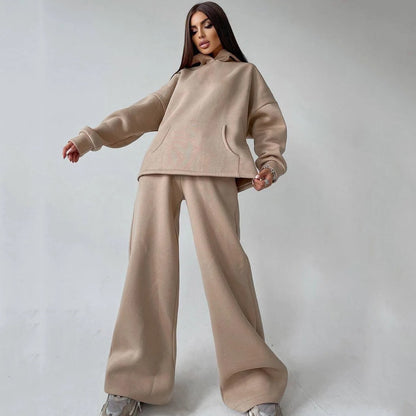 A woman posing in a beige, oversized hoodie with matching sweatpants