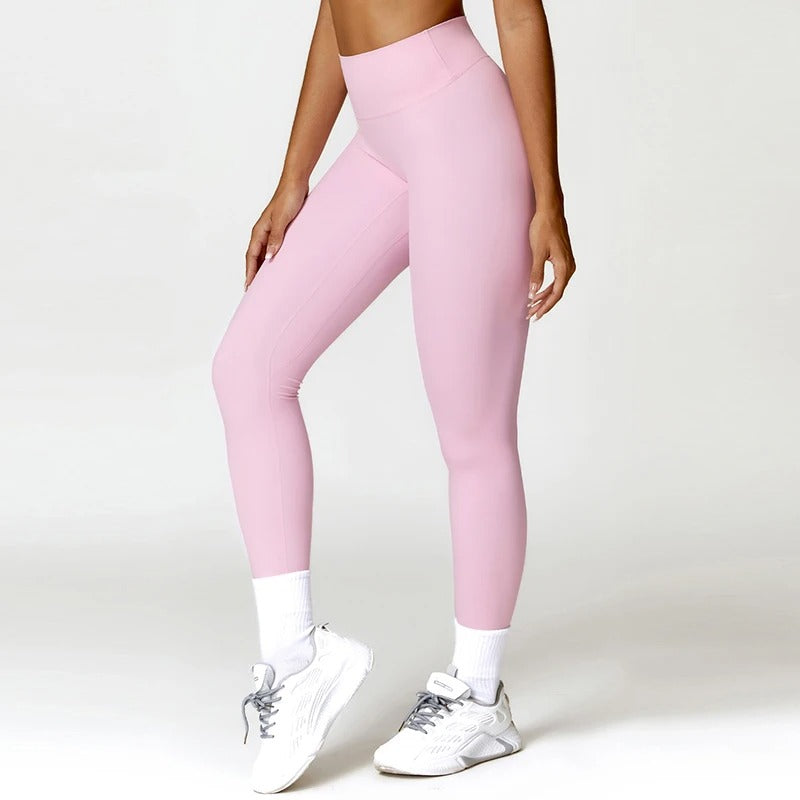 A woman posing in light pink leggings