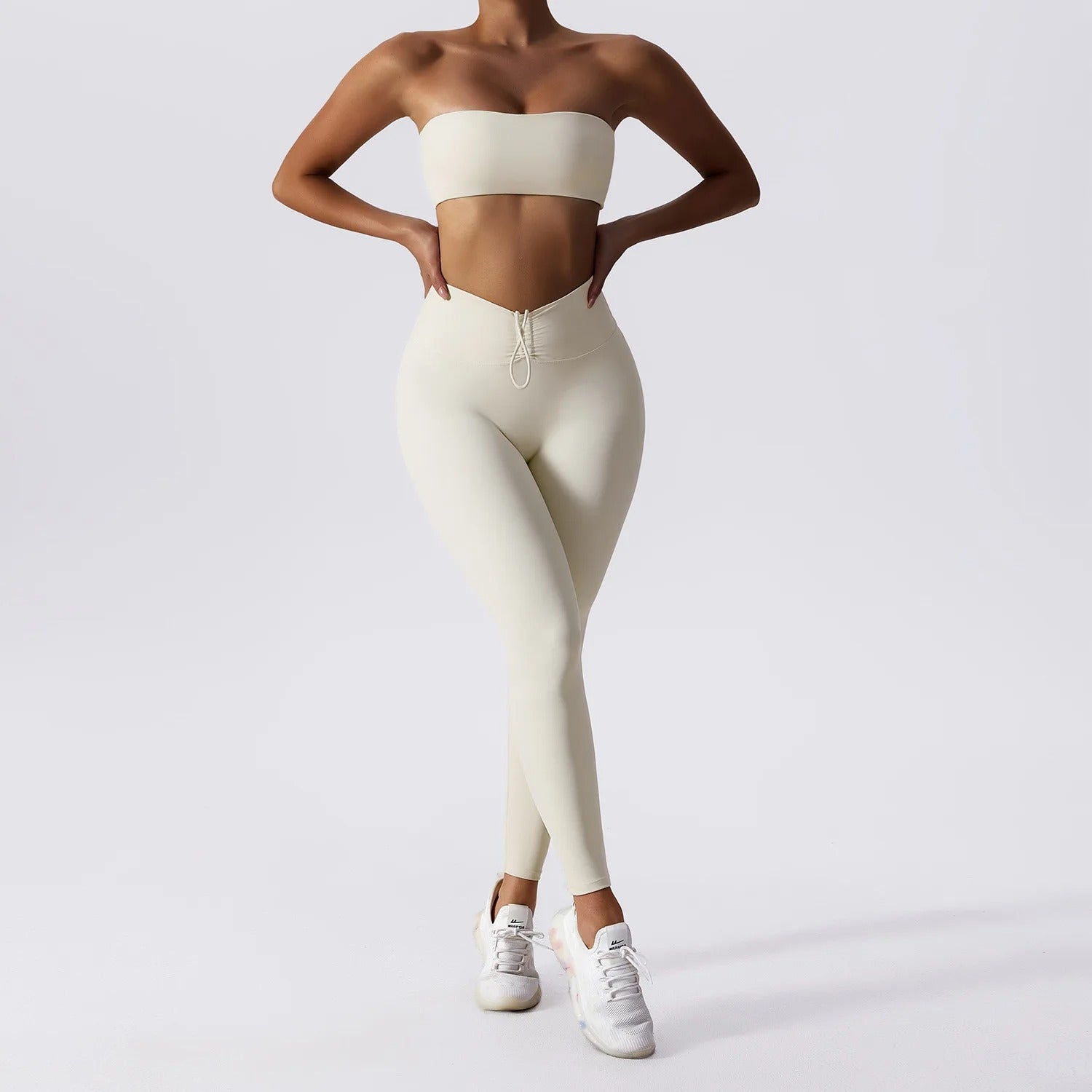 Woman posing in a white, matching workout set consisting of a sports bra and high waisted leggings