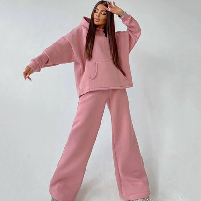 A woman posing in a pink, oversized hoodie with matching sweatpants