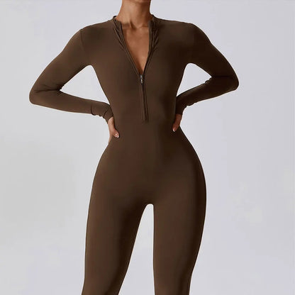 Woman posing in a long- sleeved, brown, yoga jumpsuit with a zipper