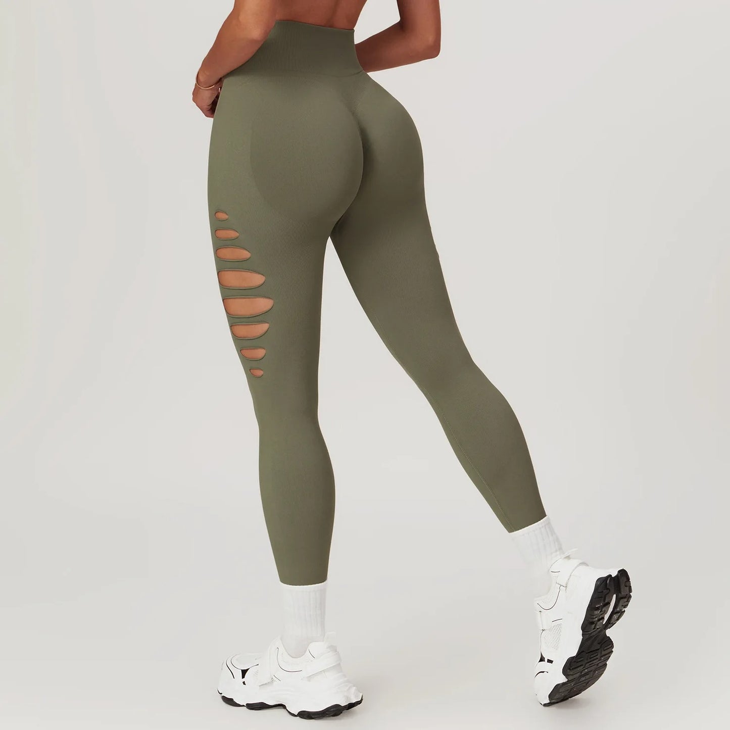 A woman in olive green yoga pants with holes on the sides