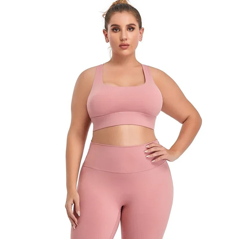 A woman posing in a pink sports bra with matching leggings