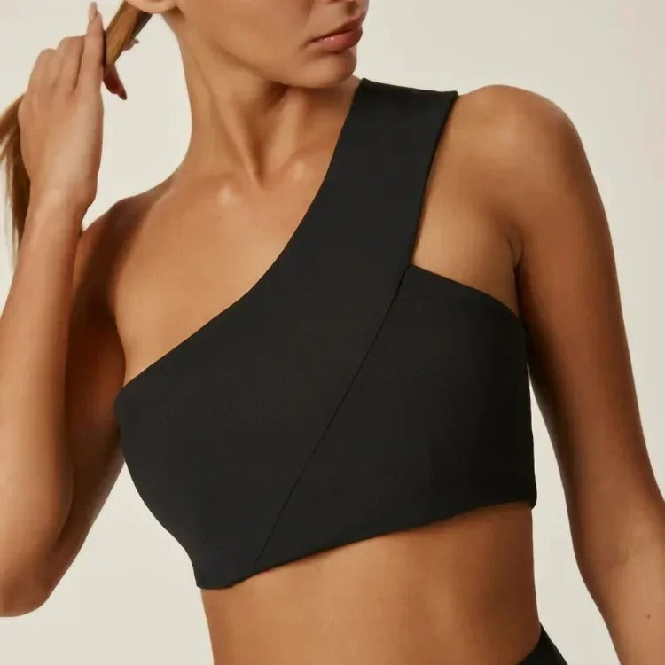 A woman posing in a black, one shoulder sports bra