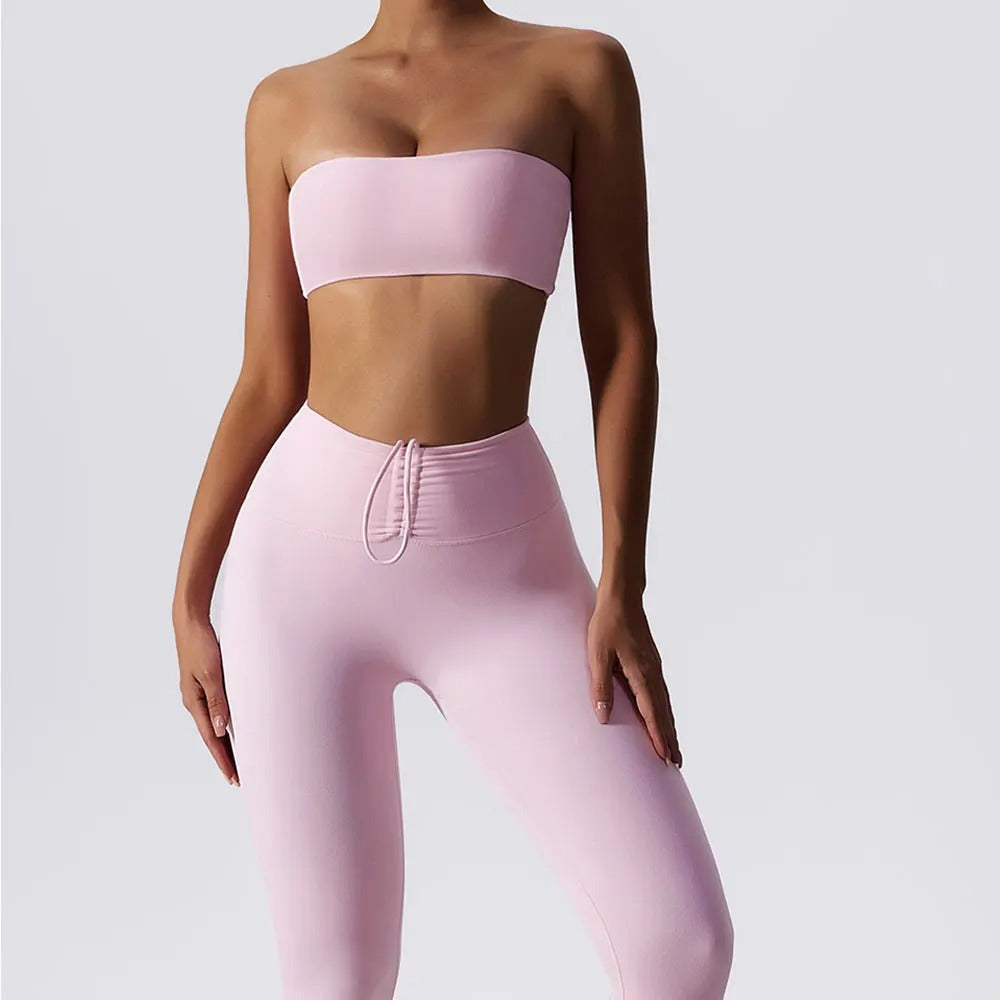 Woman posing in a light pink, matching workout set consisting of a sports bra and high waisted leggings