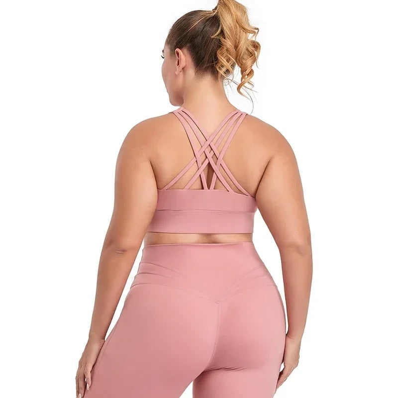 A woman posing in a pink sports bra with matching leggings