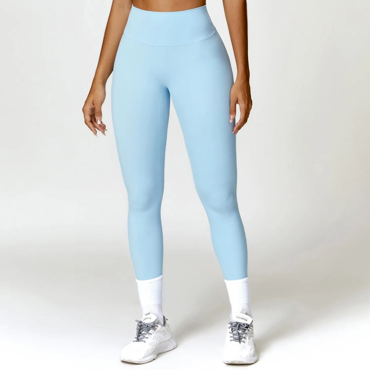 A woman posing in light blue leggings