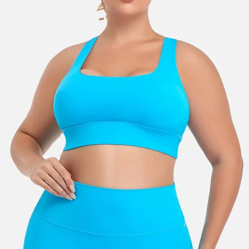 A woman posing in a light blue sports bra with matching leggings