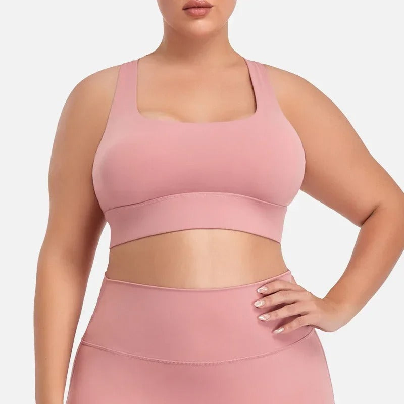 A woman posing in a pink sports bra with matching leggings