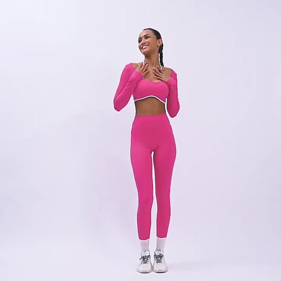 A woman posing in neon pink gym set including leggings and a sports bra