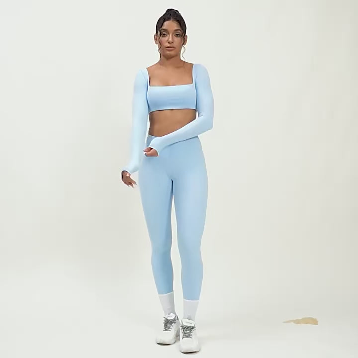 A woman posing in light blue leggings and a matching sports top