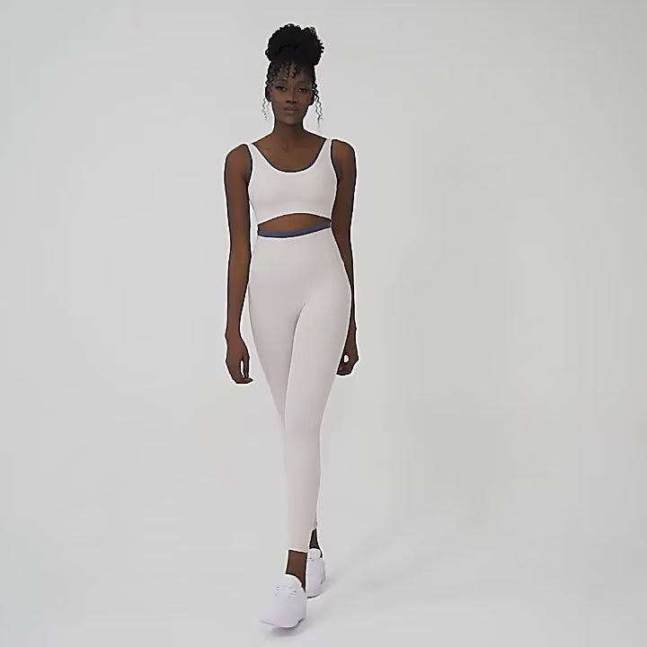 Woman posing in a white workout set consisting of leggings and a sports top