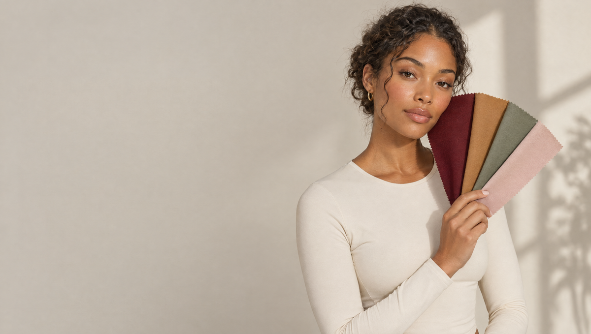 Woman holding a fan of cherry, honey, sage and blush fabric swatches beside her face in soft autumn light